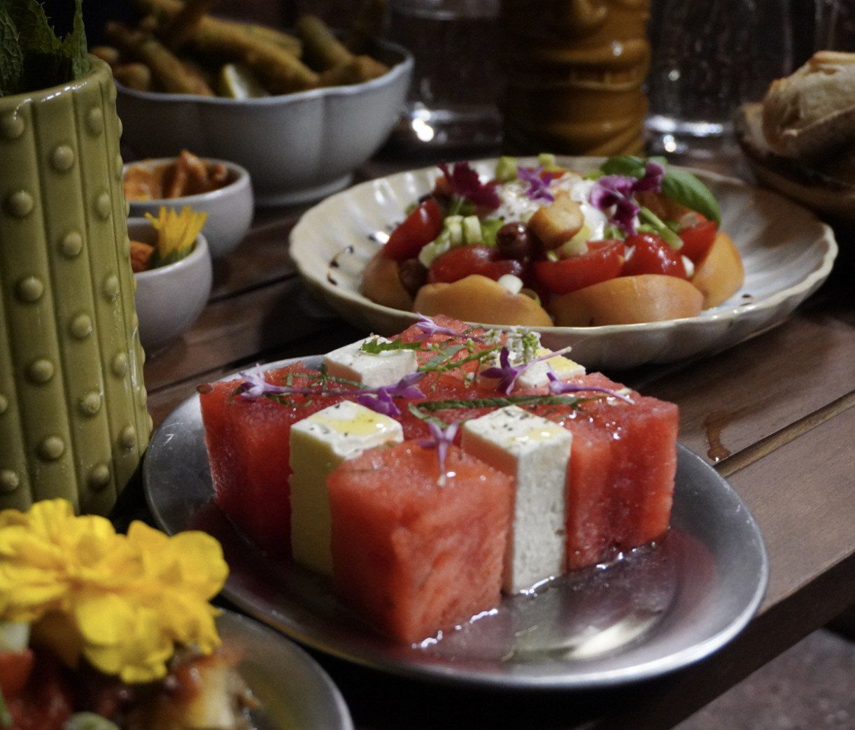 Pastèque et feta, tomates et fleurs comestibles sur une table de La Pagaille