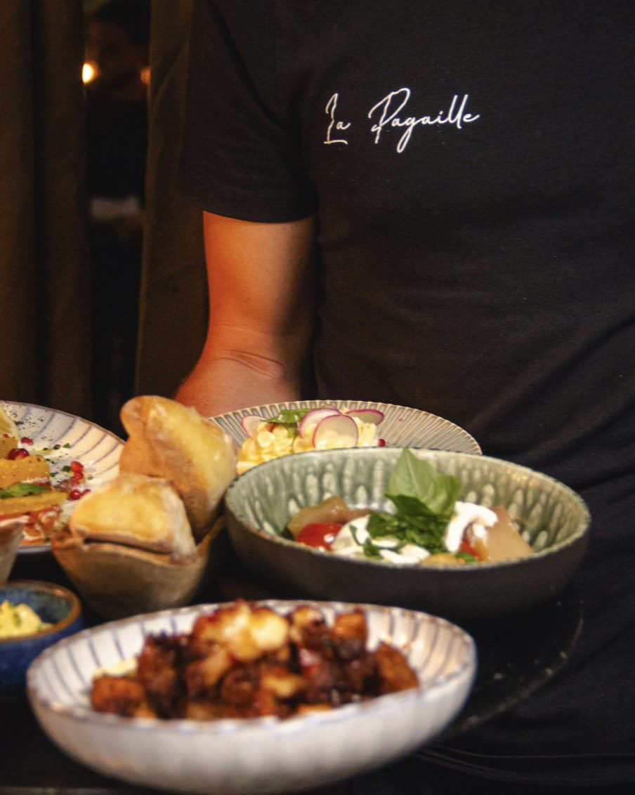 Un serveur de La Pagaille apporte plusieurs assiettes à partager
